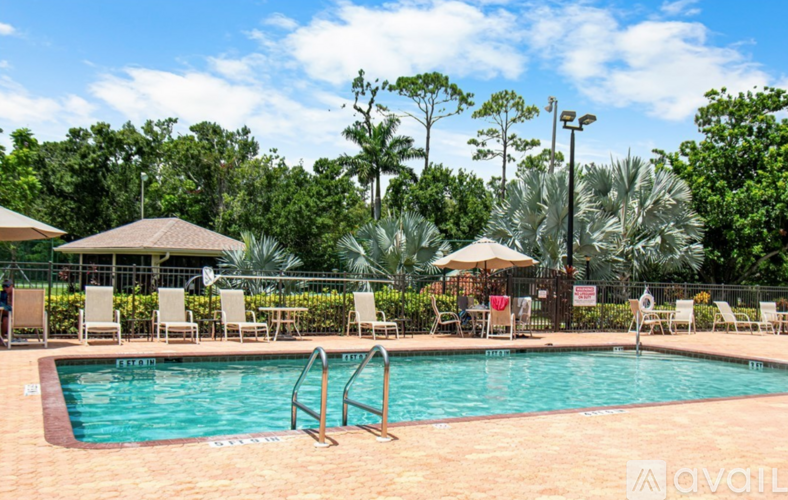A pool surrounded by trees and chairs.