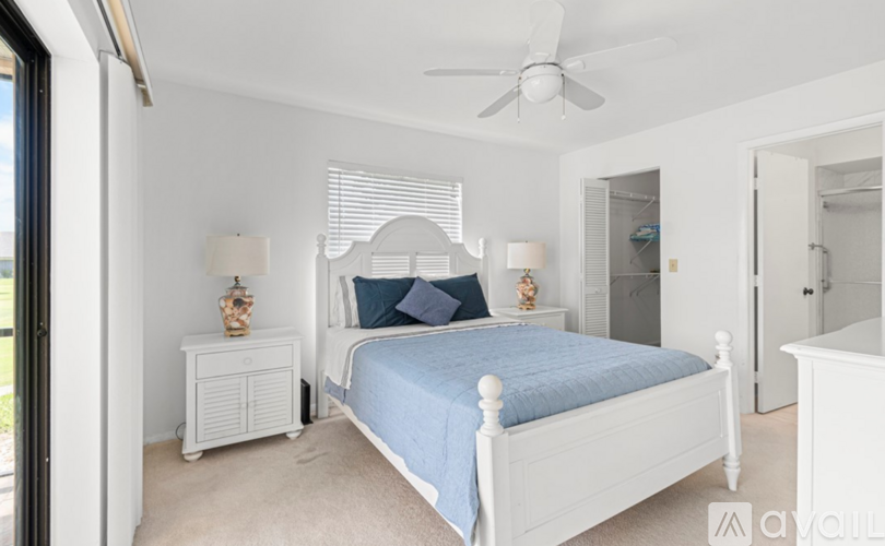 A bedroom with a white bed and a blue bedspread.