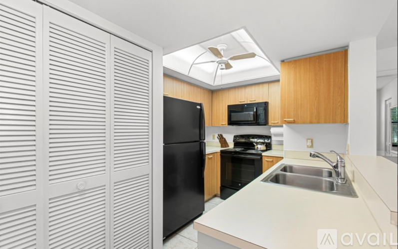 A kitchen with a black refrigerator and wooden cabinets.