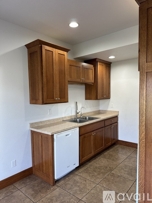 A kitchen with wooden cabinets and a white dishwasher.