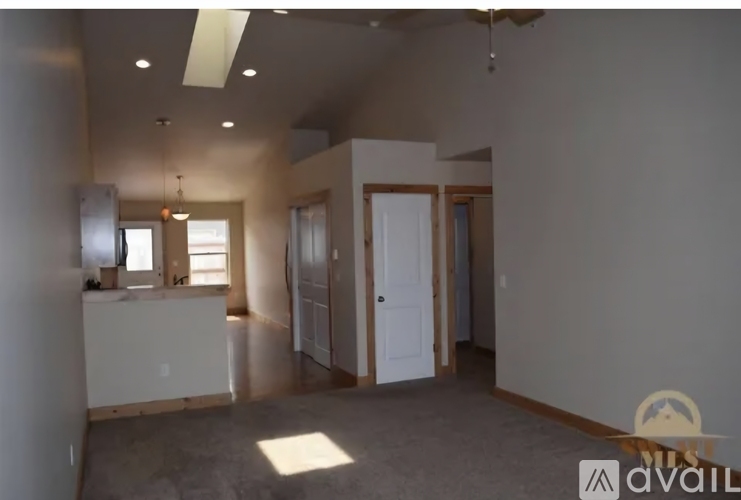A spacious room with a kitchen area and a ceiling fan.