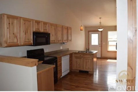 A kitchen with wooden cabinets and a black microwave.