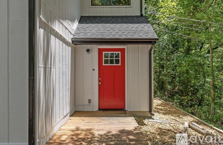 A red door is on the side of a white building.