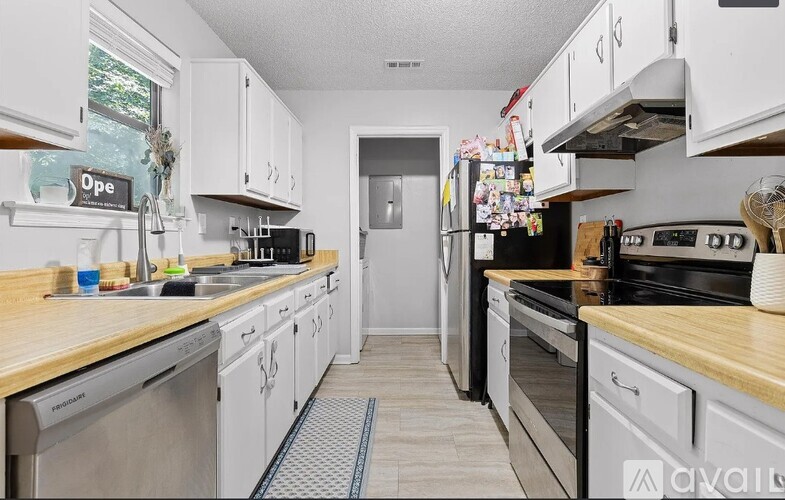 A kitchen with white cabinets and a wooden counter top.