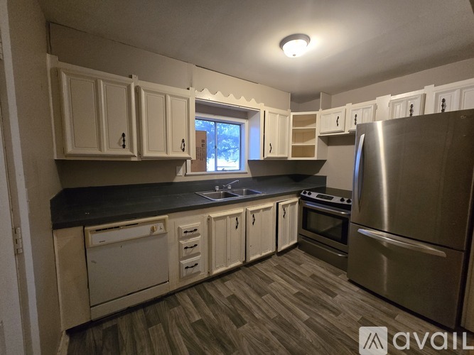 A kitchen with white cabinets and a stainless steel refrigerator.