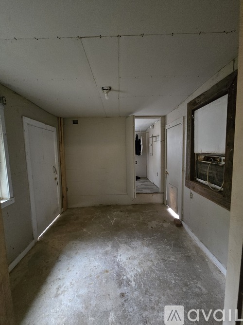 A room with a window on the right side and a door on the left side.