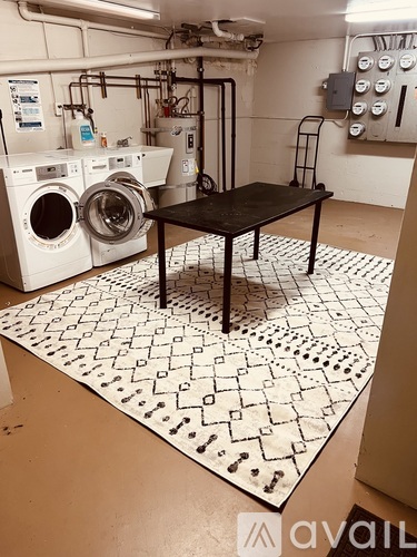 A black table is in the middle of a white tiled floor with washing machines in the background.