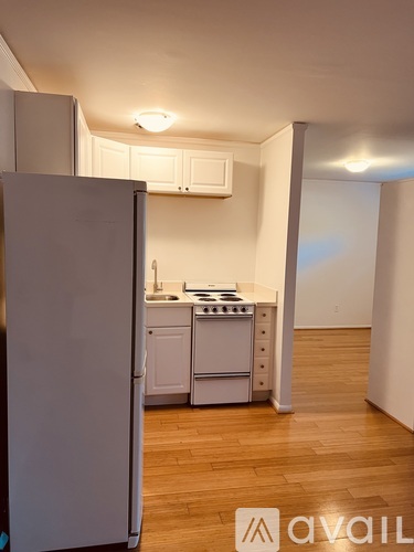 A kitchen with white appliances and wooden floors.