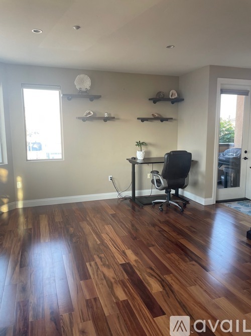 A room with wooden floors and a desk with a chair.