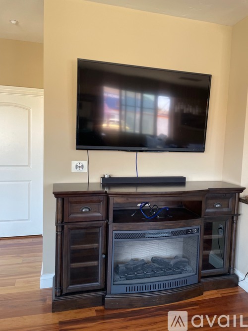 A black television is mounted above a wood fireplace.