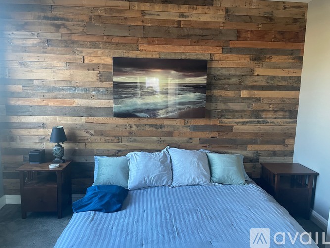 A bedroom with a wooden wall and a bed with blue bedding.