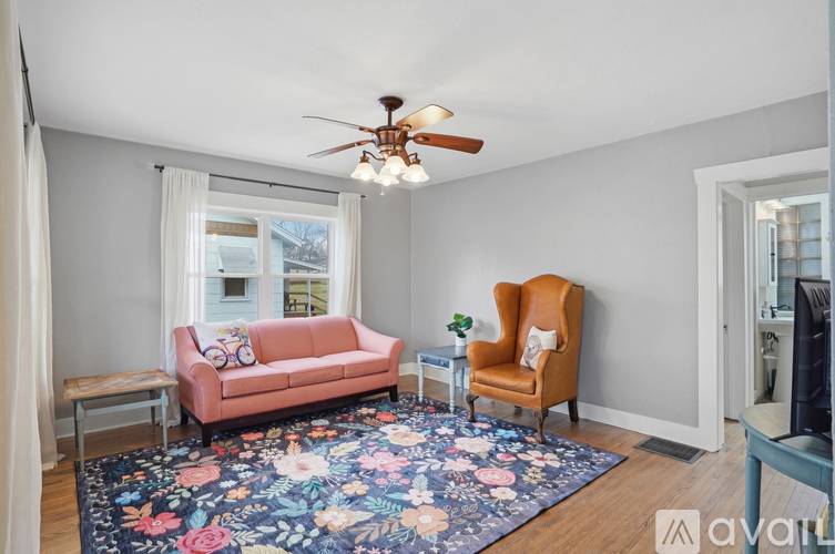 A living room with a pink couch, a chair, and a rug.