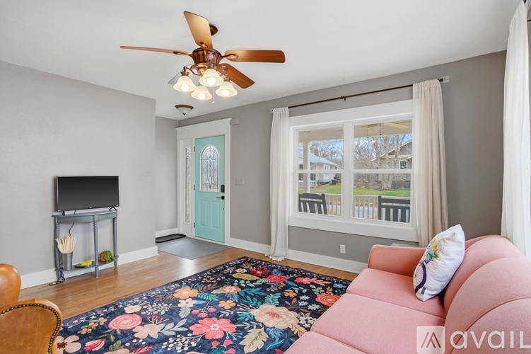 A living room with a pink couch and a ceiling fan.