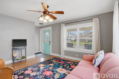 A living room with a pink couch and a ceiling fan.