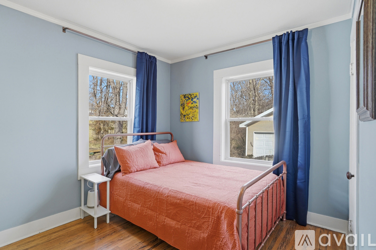 A bedroom with a bed, nightstand, and window.