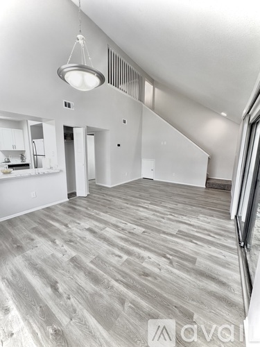 A spacious room with wooden flooring and white walls.