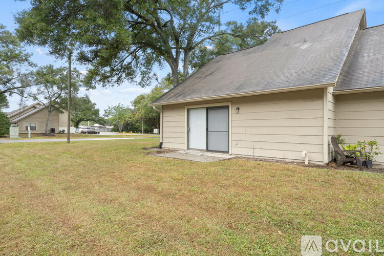 A house with a brown roof and a white door is surrounded by grass and trees.