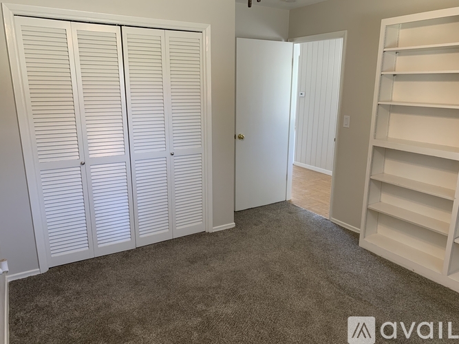 A room with white closet doors and a carpeted floor.