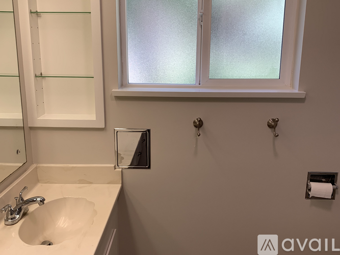 A bathroom with a sink, mirror, and frosted glass window.