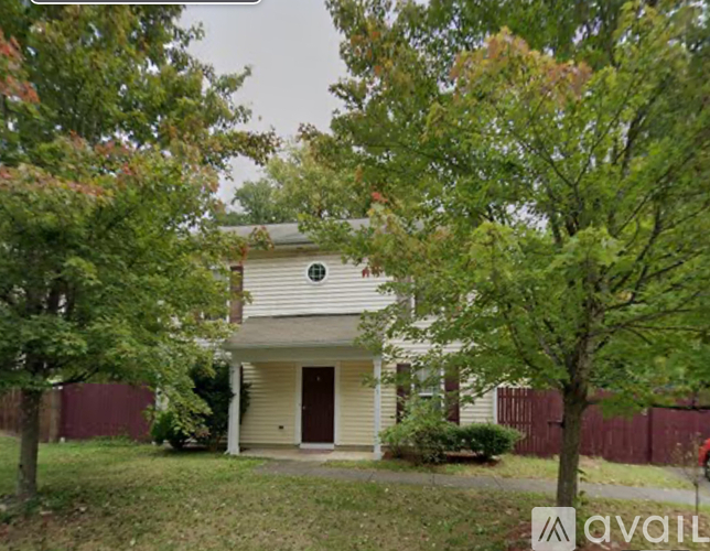 A house with a brown door is surrounded by trees.
