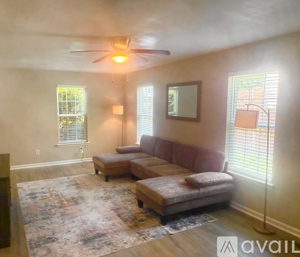 A living room with a rug, a couch, and a ceiling fan.