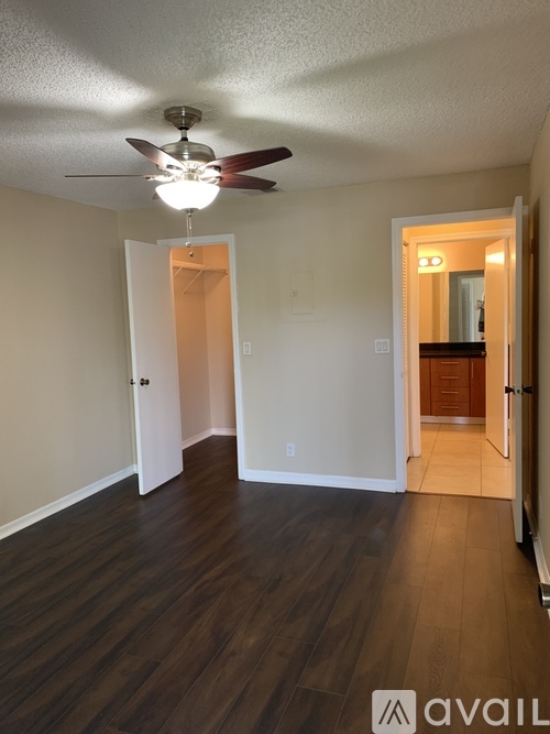 A room with a ceiling fan and wooden floors.
