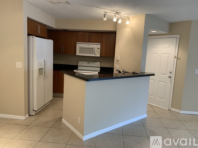 A kitchen with a white refrigerator, microwave, and oven, and a counter with a sink.