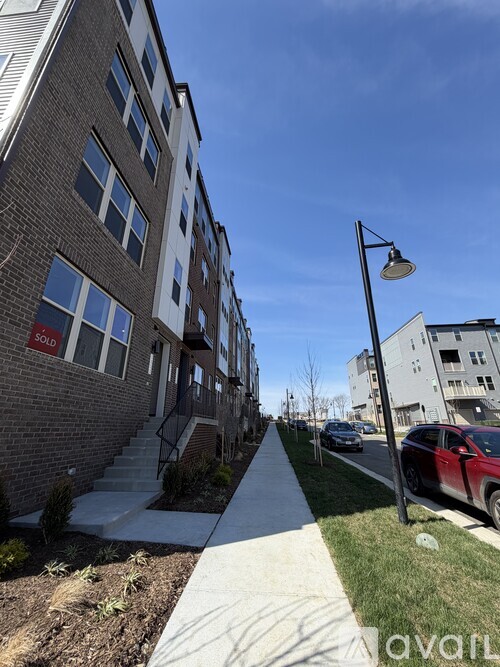 A residential street with a sidewalk and a red car parked on the side.