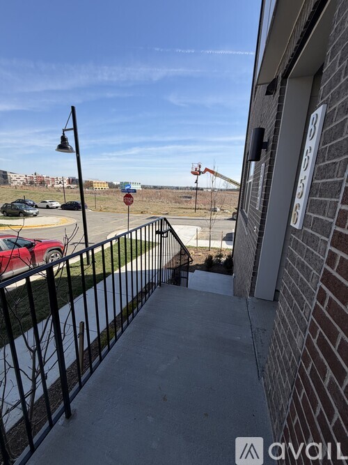 A red car is parked in a lot behind a building.