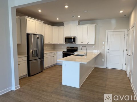 A kitchen with white cabinets and a wooden floor.