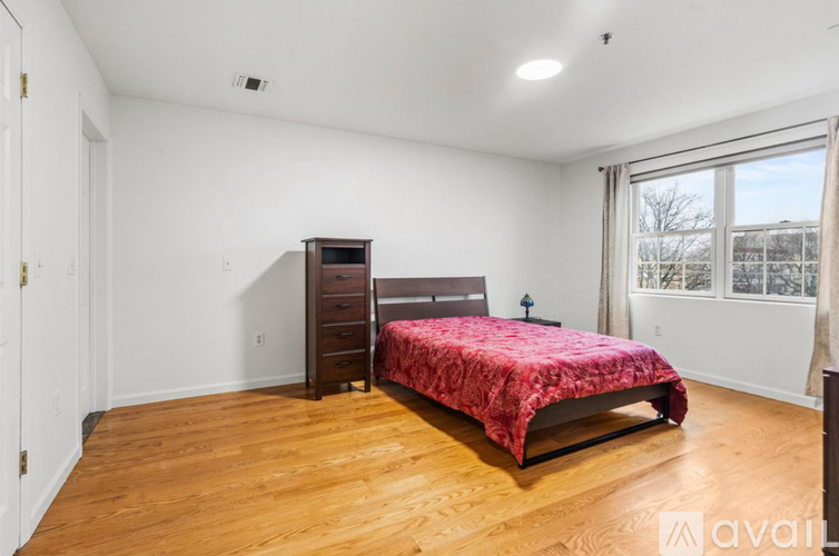 A bedroom with a bed, dresser, and window.