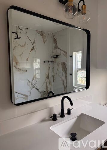 A bathroom sink under a mirror with a marble pattern.