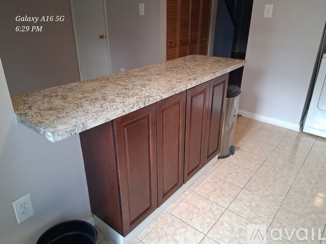A kitchen island with a granite countertop and wooden cabinets.