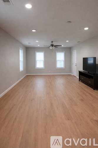 A spacious room with wooden flooring and a ceiling fan.