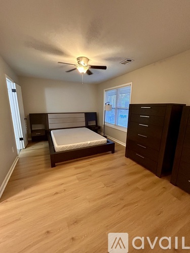 A bedroom with a bed, dresser, and window.