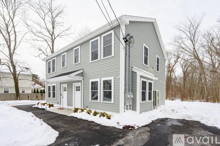 A house with a grey exterior is surrounded by snow.