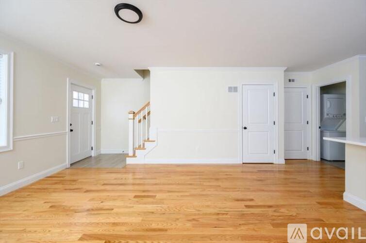A spacious room with wooden floors and white walls.