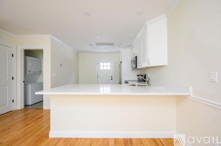 A kitchen with white cabinets and a white island.