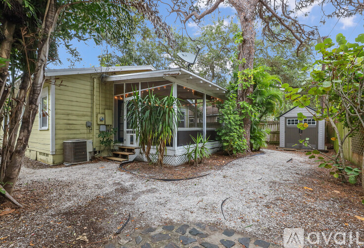 A house with a gravel driveway surrounded by trees.