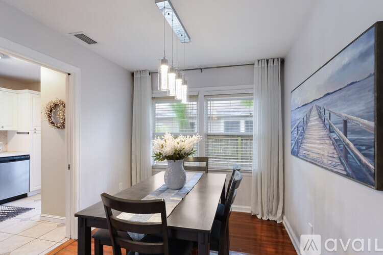 A dining room with a table set for two and a painting on the wall.