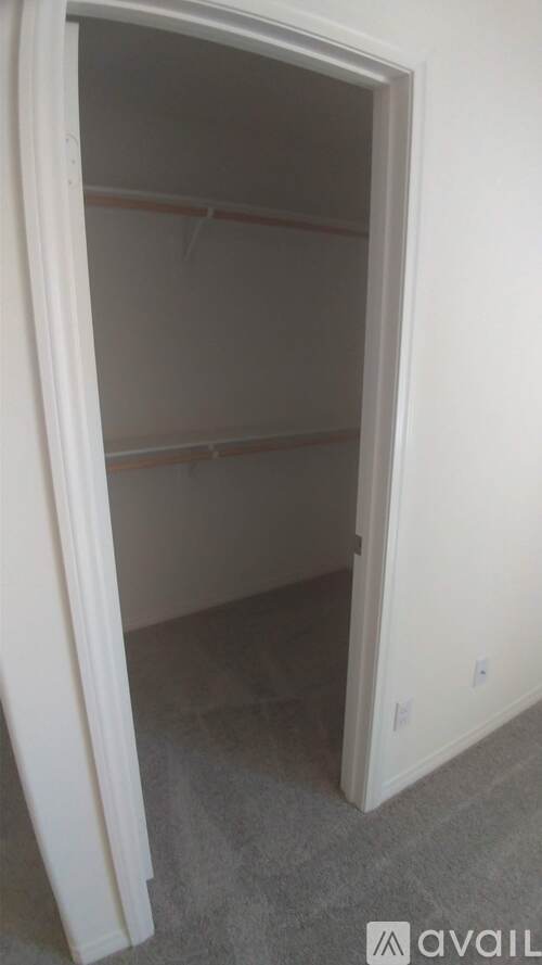 A white doorway leading to an empty room with grey carpet.