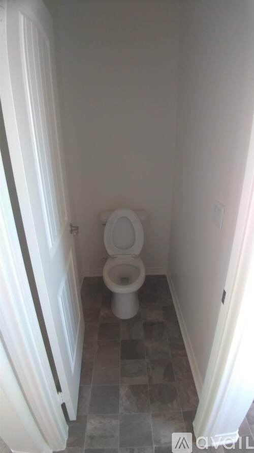 A white toilet in a small bathroom with a tiled floor.