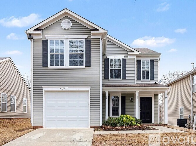 A grey house with a white garage door and black shutters.