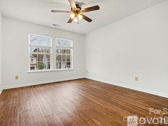 A room with a ceiling fan and wooden flooring.