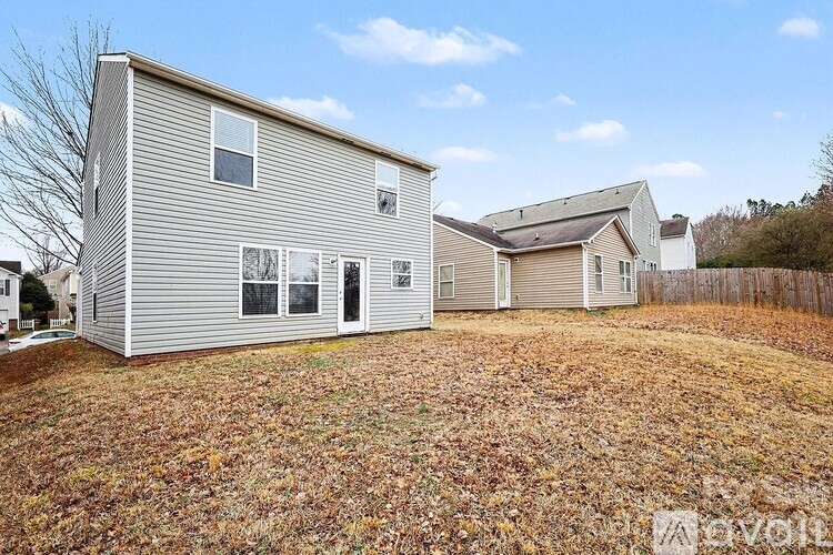 A two-story house with a garage is surrounded by a grassy area with fallen leaves.