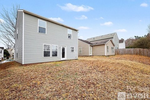 A two-story house with a garage is surrounded by a grassy area with fallen leaves.