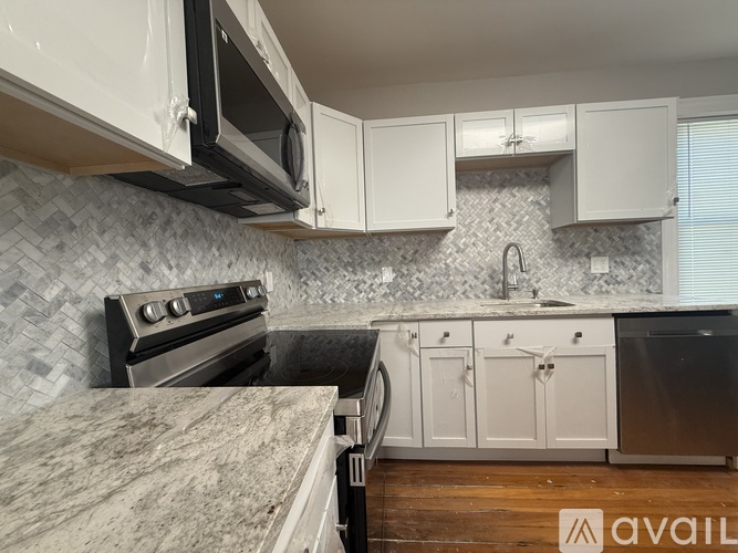 A kitchen with white cabinets and a marble countertop.