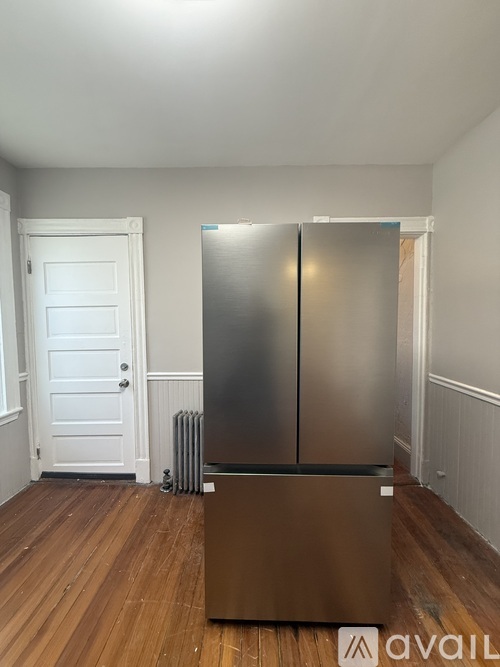 A kitchen with a stainless steel refrigerator and wooden floors.