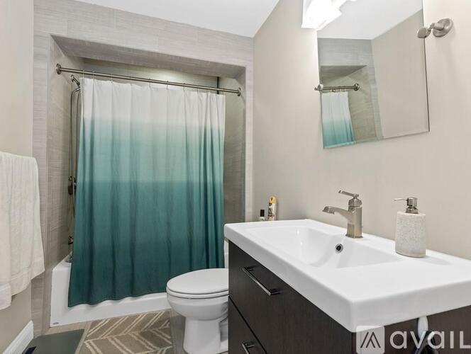 A bathroom with a white sink, toilet, and a shower with a blue curtain.