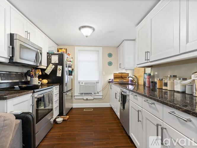 A kitchen with white cabinets and a black countertop.